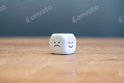 Preview: A white cube with a sad face on one side and a happy face on the other side sits on a wooden table.