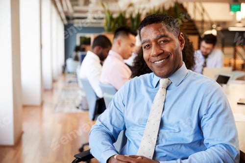 Preview: Portrait Of Mature Businessman In Modern Office With Colleagues Meeting Around Table In Background