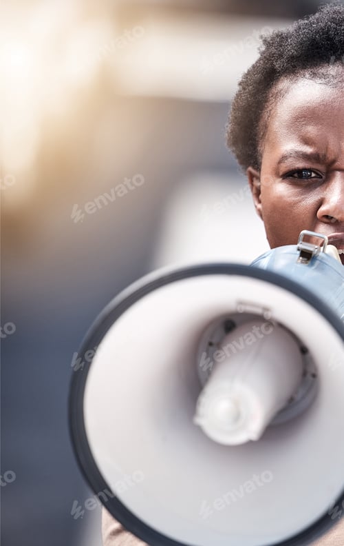 Preview: We will not be denied. Shot of a young woman shouting through a megaphone at a protest.