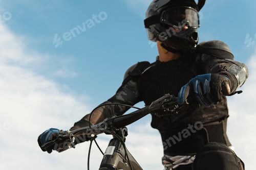 Preview: Downhill rider fully equipped with protective gear riding his bicycle