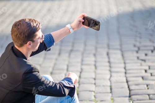 Preview: Close up of male hands is holding cellphone outdoors on the street. Man using mobile smartphone