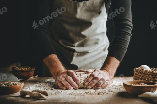 Preview: Young man kneading dough on dark background.