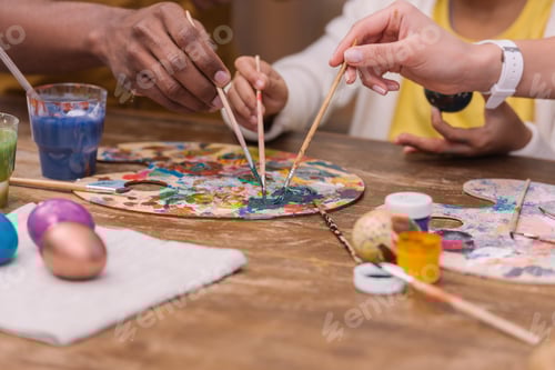 Preview: cropped image of african american parents and daughter putting paint brushes on palette, easter