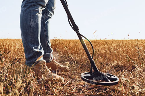 Preview: Man with metal detector equipment searching for metal goods in the field