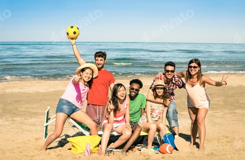 Preview: Group of multiracial happy friends having fun with beach sport games