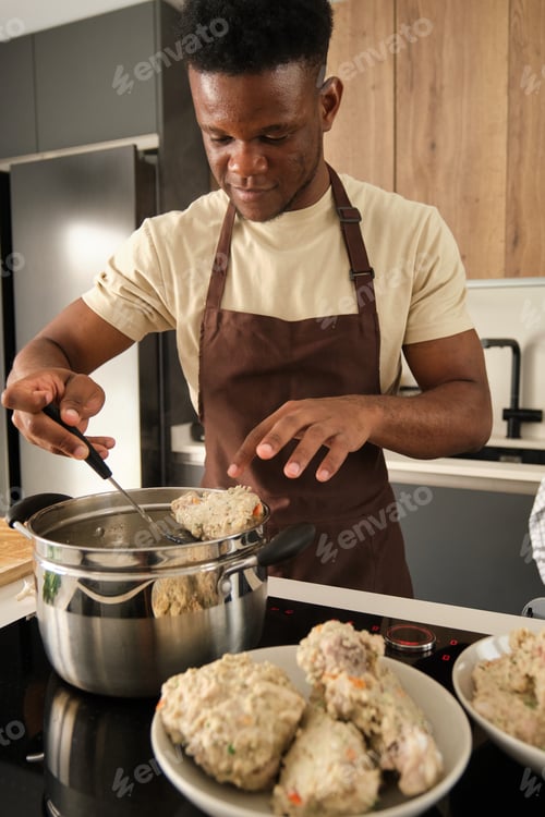 Preview: Young african man preparing boiled chicken mince with vegetables recipe.