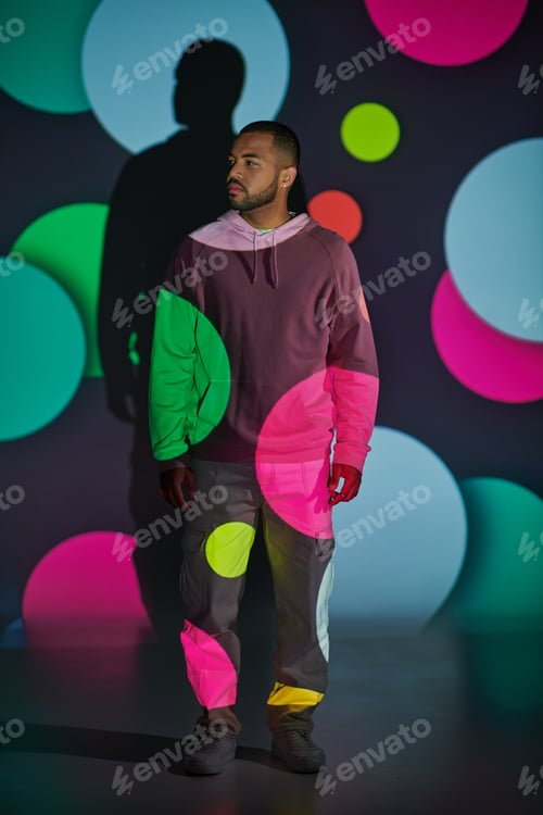Preview: handsome man in pink hoodie standing and looking away in digital projector lights, fashion concept