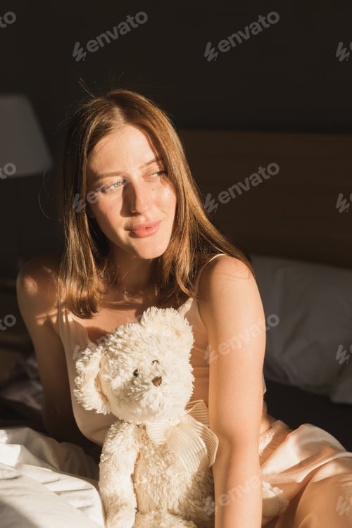 Preview: Girl is waking up in morning stretches in bed and sun shines from the window. Happy young woman