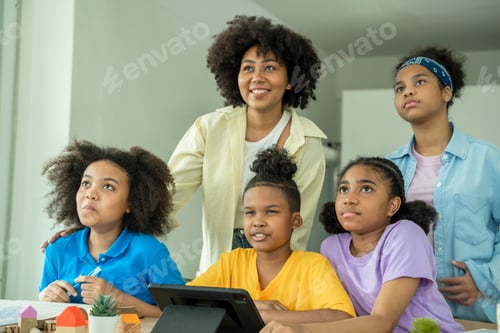 Preview: Young African American children sitting at school desk attentively listening to his teacher.