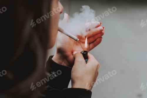 Preview: Selective closeup shot of a female lighting up a cigarette with a lighter