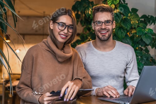 Preview: Portrait of two freelancers using laptop computer during lunch sitting in cafe