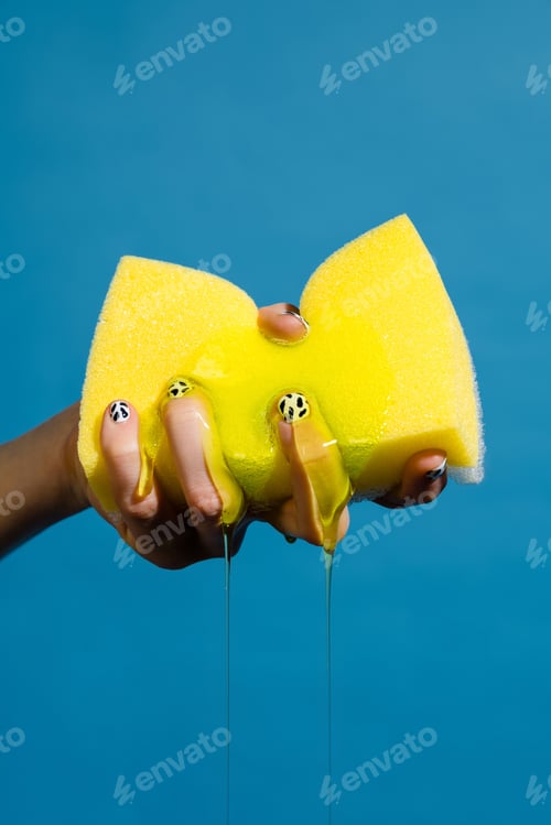 Preview: Closeup photo of hand and sponge with cleaning gel isolated over blue wall