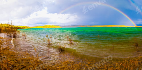 Preview: Rainbow and dark clouds over large lake