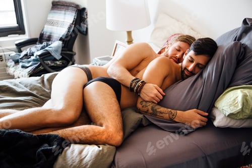 Preview: Male couple, partially dressed, lying together on bed, sleeping