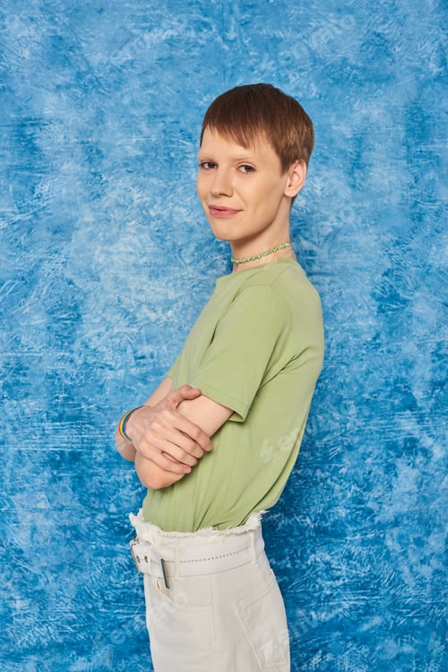Preview: Smiling queer person in casual clothes crossing arms and smiling at camera while celebrating pride