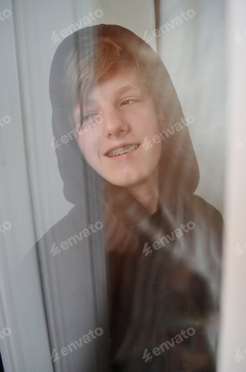 Preview: smiling teenager sitting near the window