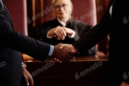 Preview: Close-up of two opposite sides of court case shaking hands against judge
