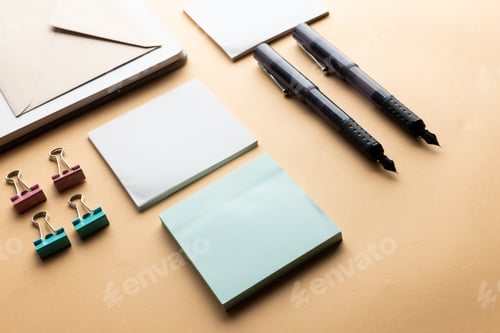 Preview: Flat lay of black pens, envelope, paper clips and memo notes with copy space on yellow background