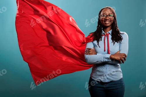Preview: Mighty looking tough superhero woman wearing red hero costume cape standing with arms crossed on