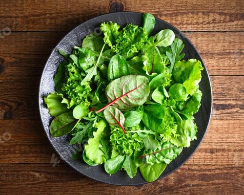 Preview: Fresh salad greens arranged on a black plate with curly lettuce leaves