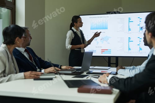 Preview: Young Caucasian Woman Presenting Business Data to Diverse Colleagues