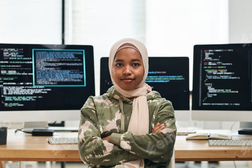 Preview: Young successful IT engineer in hijab looking at camera against workplace
