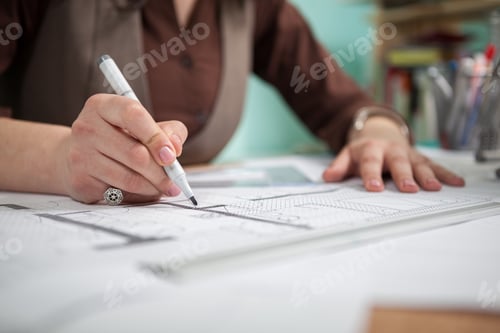 Preview: Close up of architect woman at her table drawing on blueprints