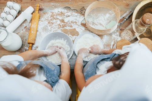 Preview: Top view of two little girls in blue chef uniform that preparing food on the kitchen