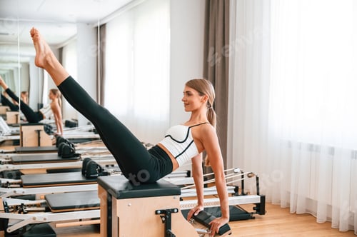 Preview: Sitting on the special chair. Young woman in fitness center is doing exercises
