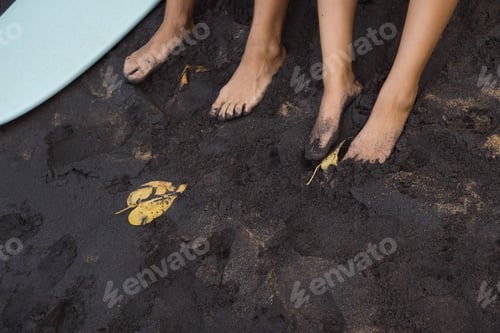 Preview: Foots of couple in love sitting on black sand after surfing. Beach travel in Sri Lanka