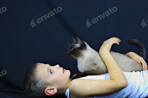 Preview: Closeup shot of a Caucasian boy in a hat holding a cat on an isolated background