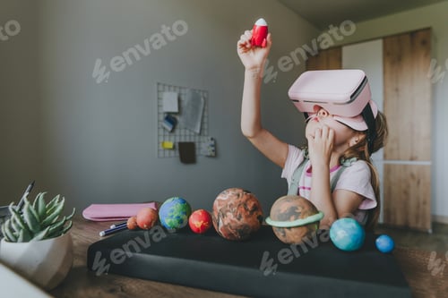 Preview: Little girl using VR glasses at home for learning Solar system planets