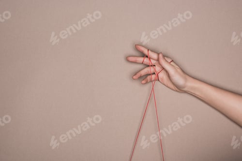 Preview: Top view of female hand with red string on beige background
