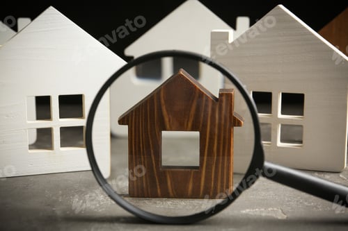 Preview: Magnifying glass and house models on grey stone table. Search concept