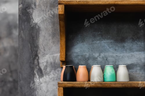 Preview: Different colorful coffee cups on wooden shelf in cafe. Background of gray concrete cement wall
