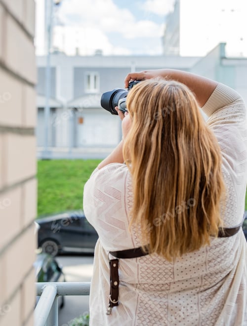 Preview: Body positive. Portrait of plus size woman taking pictures with a camera outdoors