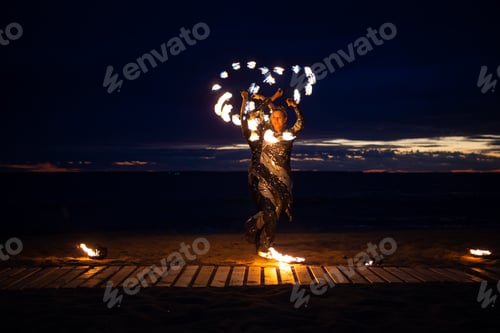 Preview: Two girls light a sparkler on the beach at dusk.