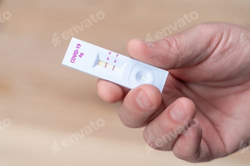 Preview: Man's hand holding a positive coronavirus test