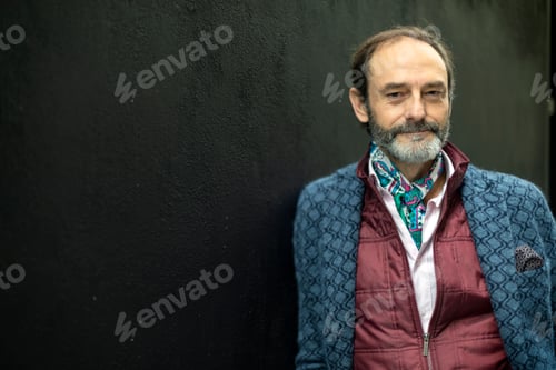 Preview: portrait of senior man with expression of well-being with a black background outdoors