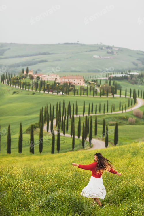 Preview: Woman in red sweater and white skirt on background on spring Tuscany landscape