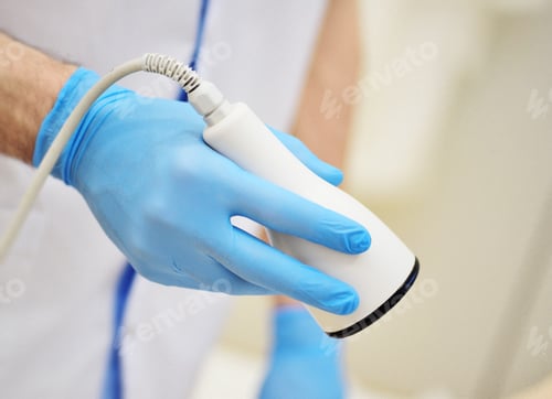 Preview: cosmetologist holds an ultrasound cavitation device in his hands - a procedure for removing fat