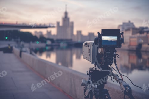Preview: A professional video camera stands on a tripod recording the city