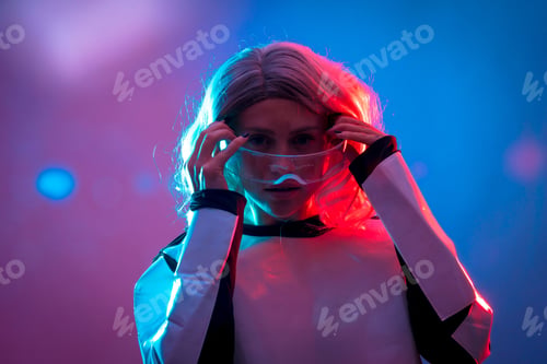Preview: Woman putting on futuristic glasses under blue and red lights - the concept of virtual reality