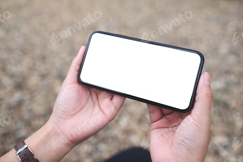 Preview: Mockup image of a woman holding mobile phone with blank white desktop screen in the outdoors