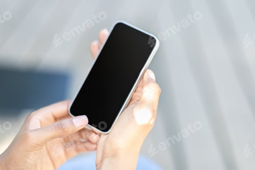 Preview: Cropped of black woman hands using smartphone, blurred outdoor background