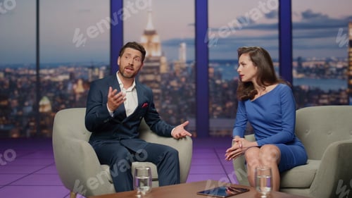 Preview: Two presenter talking tv show sitting armchairs studio. Bearded man telling news