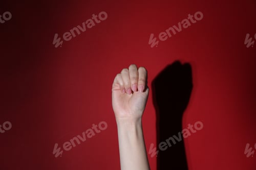 Preview: SOS gesture. Woman showing signal for help on red background, closeup