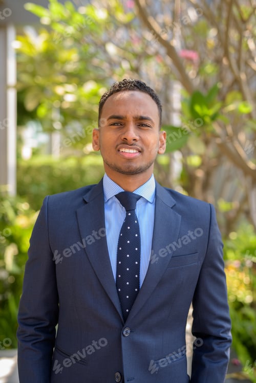 Preview: African businessman wearing suit and smiling outdoors vertical shot