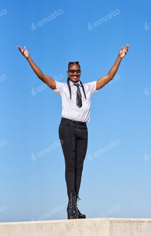 Preview: Androgynous businessperson celebrating success with open arms under blue sky