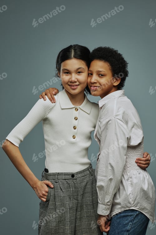 Preview: Two adorable intercultural schoolgirls in white casual tanktops